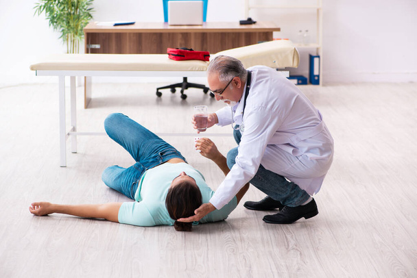 Viejo médico experimentado y joven paciente masculino acostado en el suelo - Foto, Imagen