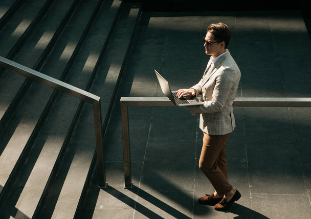 young business man spending time outdoors at the city, using laptop computer on stairs - Foto, Bild