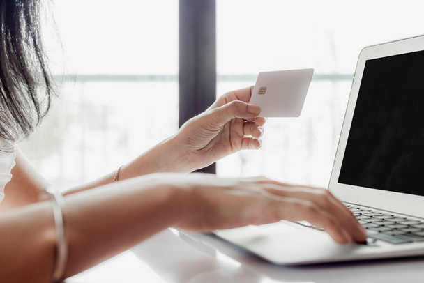 Mano della donna in possesso di una carta di credito e utilizzando il computer per lo shopping online e il concetto di pagamento
 - Foto, immagini