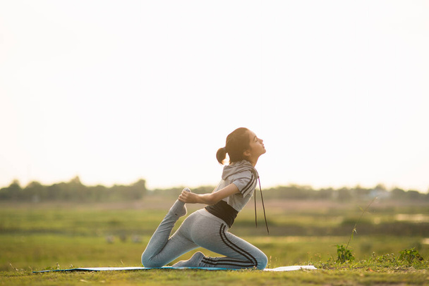 Egy fiatal nő portréja, amint jógázik odakint, napfényes fényben.. - Fotó, kép