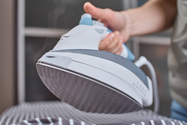 Steam boost on modern iron. Woman ironing clothes with modern iron - Foto, Bild