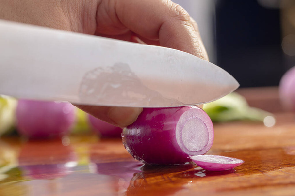 Chef close-up está cortando cebola vermelha
 - Foto, Imagem