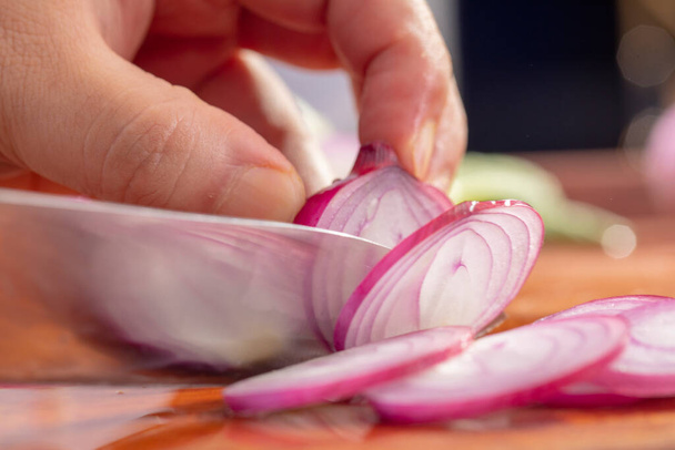 Chef close-up está cortando cebola vermelha
 - Foto, Imagem