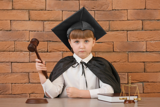 Портрет маленького судьи сидящего за столом на кирпичном фоне
 - Фото, изображение