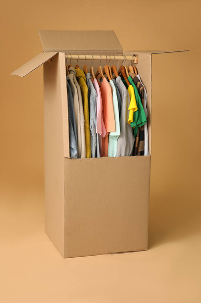 Moving box with clothes on color background - Photo, image