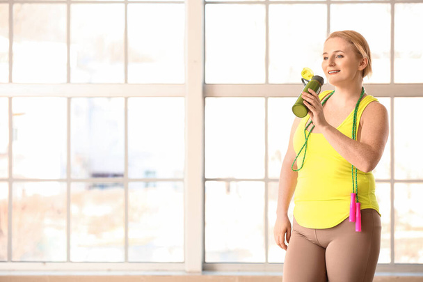Woman with excess weight drinking water in gym - Foto, Bild