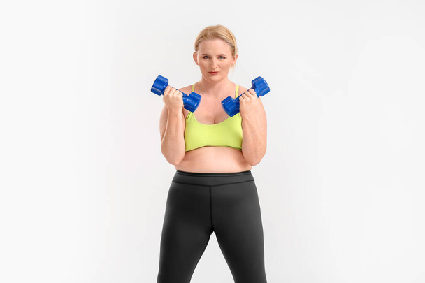 白い背景で余分な体重のトレーニングを持つ女性 - 写真・画像