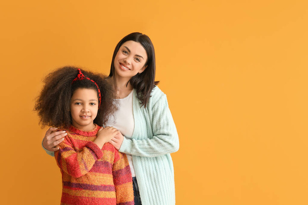 Glückliche Frau mit kleinem Adoptivmädchen auf farbigem Hintergrund - Foto, Bild