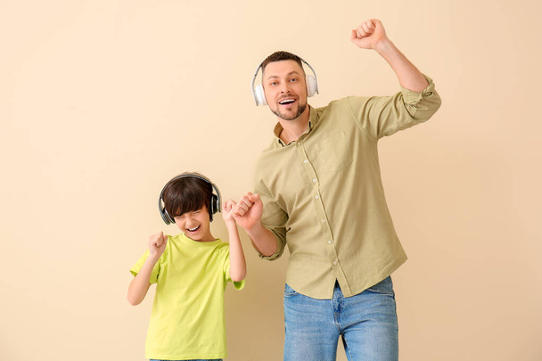 Father and little son listening to music on color background - Fotó, kép