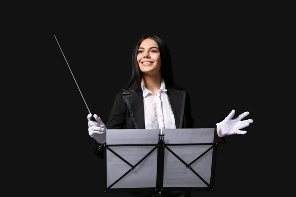 Junge Dirigentin auf dunklem Hintergrund - Foto, Bild