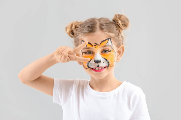 Funny little girl with face painting on light background - Photo, Image