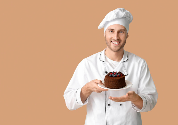 Männlicher Konditor mit leckerem Dessert auf farbigem Hintergrund - Foto, Bild
