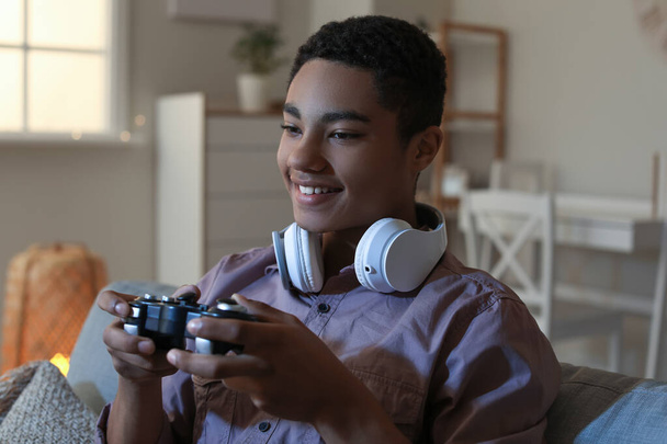 African-American teenage boy playing video game at home in evening - Fotografie, Obrázek