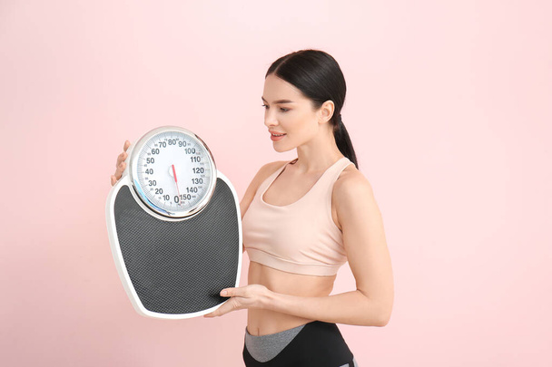 Young woman with measuring scales on color background - Photo, Image