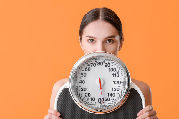 Mladá žena s měřícími váhami na barevném pozadí - Fotografie, Obrázek