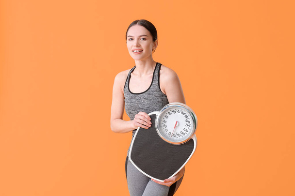 Young woman with measuring scales on color background - Photo, Image