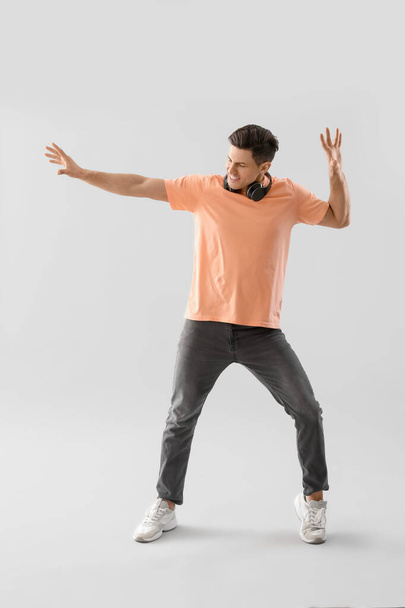 Schöner junger Mann tanzt vor hellem Hintergrund - Foto, Bild