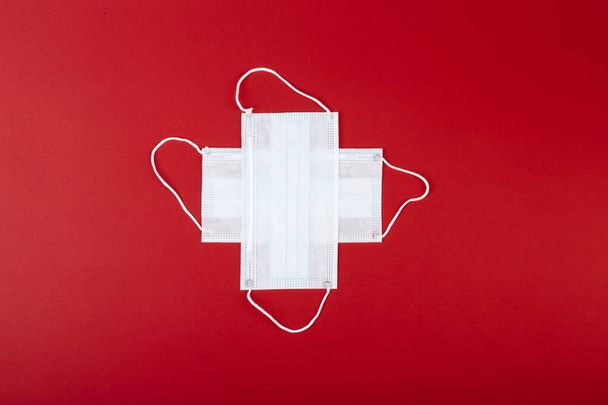 healthcare, medicine and charity concept: cross made from two white surgical masks for protection from COVID-19. Looks like a Flag of Switzerland. - Foto, afbeelding