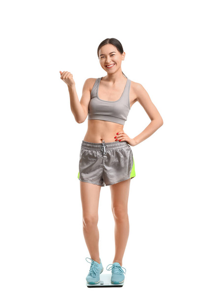 Mujer joven midiendo su peso sobre fondo blanco
 - Foto, Imagen
