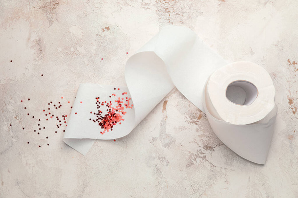 Papier toilette avec des paillettes rouges sur fond clair. Concept des hémorroïdes
 - Photo, image