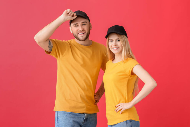 jong paar in stijlvolle caps op kleur achtergrond - Foto, afbeelding