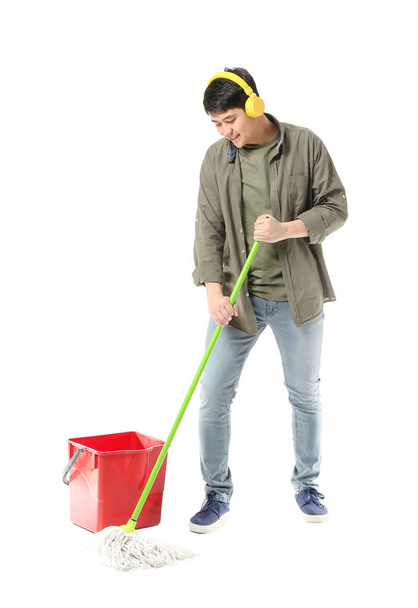 Young man with mop and headphones on white background - Φωτογραφία, εικόνα