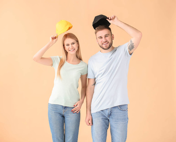 Mladý pár se stylovými čepicemi na barevném pozadí - Fotografie, Obrázek