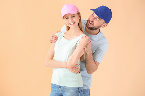 Young couple in stylish caps on color background - 写真・画像