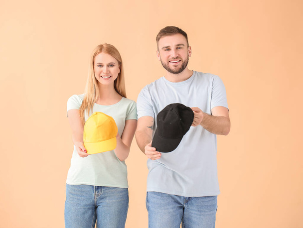 Young couple with stylish caps on color background - Photo, Image