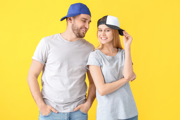 Young couple in stylish caps on color background - Photo, Image