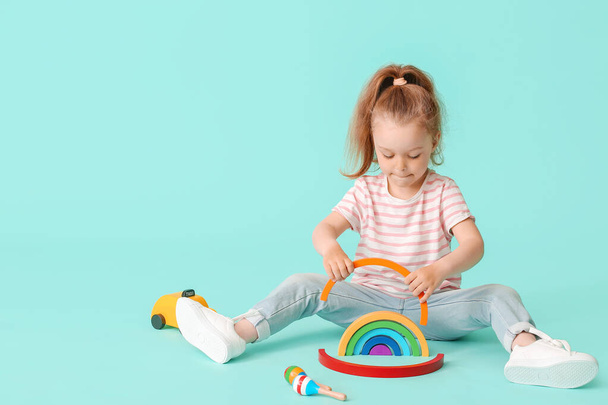 Klein meisje met speelgoed op kleur achtergrond - Foto, afbeelding