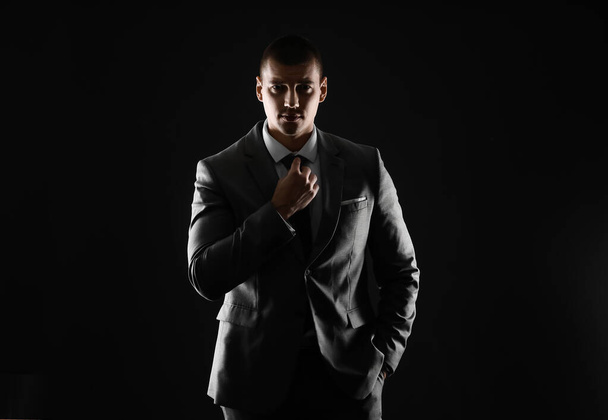 Silhouette of handsome young man in elegant suit on dark background - Photo, Image