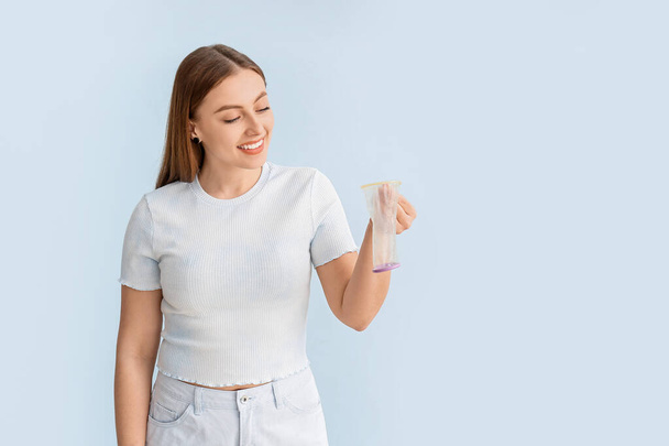 Young woman with female condom on color background - Zdjęcie, obraz