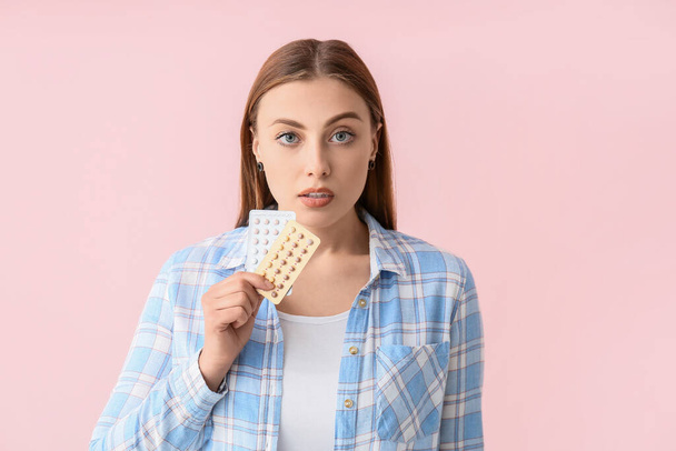 Jonge vrouw met anticonceptiepillen op kleur achtergrond - Foto, afbeelding
