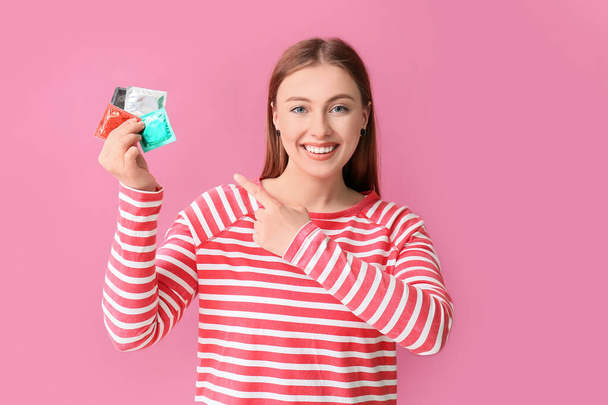 Young woman with condoms on color background - Photo, image