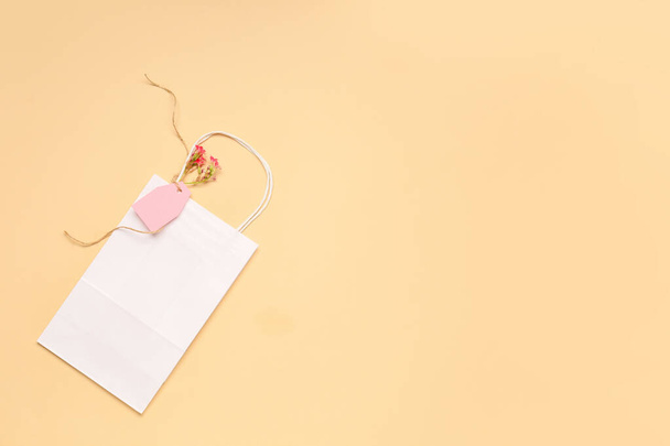 Бумажная сумка с цветами и биркой на цветном фоне
 - Фото, изображение