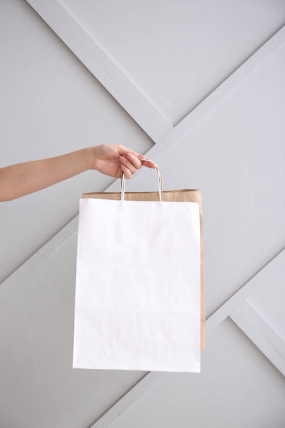 Hand with paper bags on light background - Photo, image