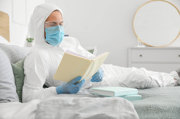 Mann im Biohazard-Anzug liest zu Hause Buch - Foto, Bild