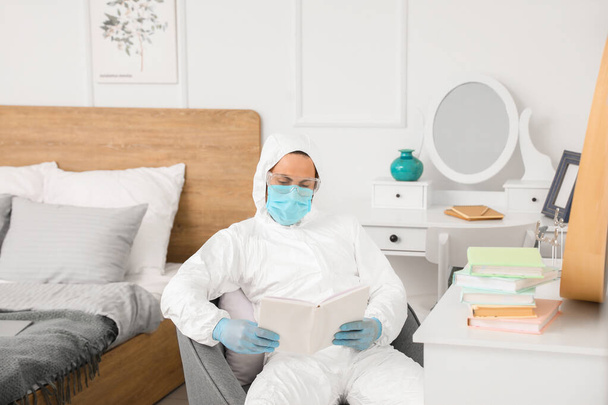 Mann im Biohazard-Anzug liest zu Hause Buch - Foto, Bild