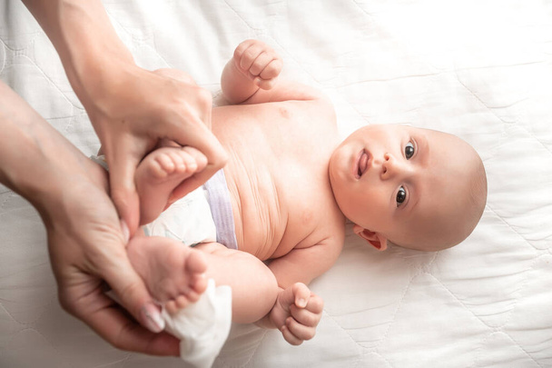 Neonato ottenere un cambio pannolino: mamma pulire il sedere del bambino con baby wipe. emozioni del neonato. Concetto Igiene pulizia wipe, puro, pulito
. - Foto, immagini