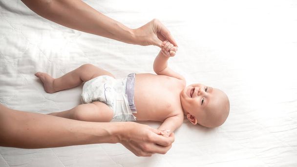Mãe ou terapeuta faz massagem ao bebê em casa. Conceito de cuidados de saúde e medicina
. - Foto, Imagem
