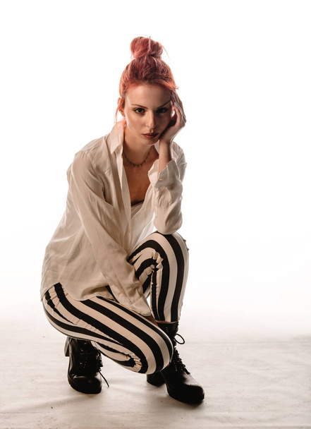 Body shot of a stylish woman posing in trendy black and white stripe pants isolated on white background - Foto, immagini