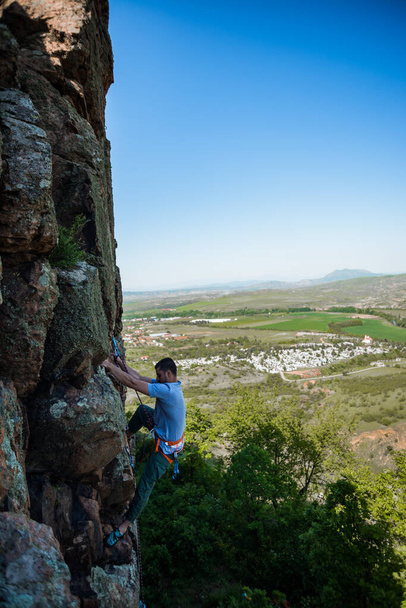 escalador de rocha sobe o penhasco usando cordas e equipamentos, o emprego de escalada esportiva - Foto, Imagem