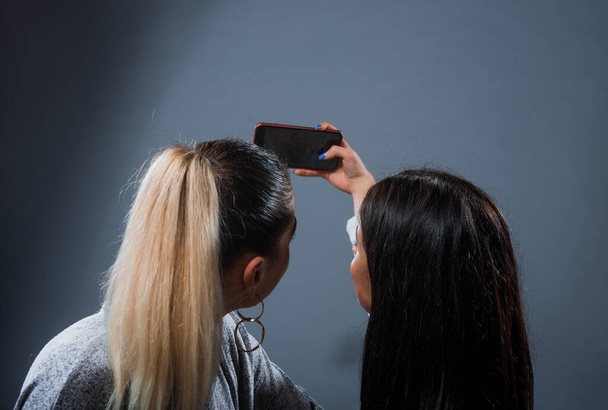 wo belos modelos femininos encantadores tomar uma selfie com um smartphone
 - Foto, Imagem
