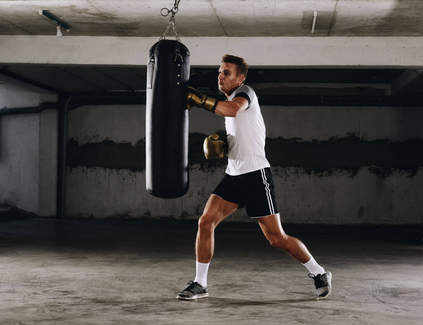Jovem atleta treino de boxe no ginásio de fitness em fundo escuro. Homem atlético formação hard.Kick conceito de boxe
 - Foto, Imagem