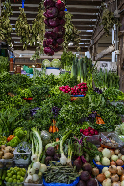 Bitkilerle dolu bir market tezgahı ve çeşitli taze sebzeler. Sağlıklı beslenme ve vejetaryenlik. Ön manzara. Dikey. - Fotoğraf, Görsel