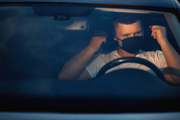 Молодий чоловік у масці для обличчя в машині
 - Фото, зображення