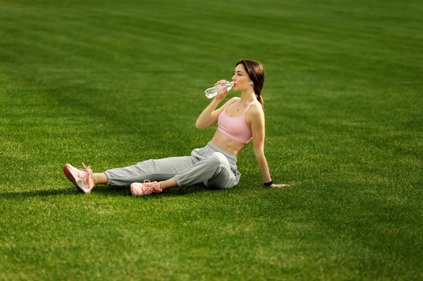 Young fit woman with water  on stadium  - Photo, image