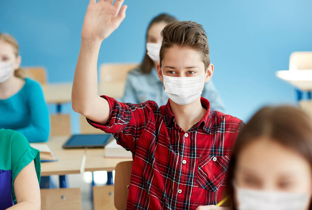 student boy in mask with raised hand at school - Foto, immagini