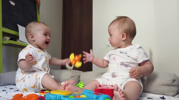 Braterskie bliźniaczki siostry, bawiące się zabawkami na podłodze w domu - Materiał filmowy, wideo